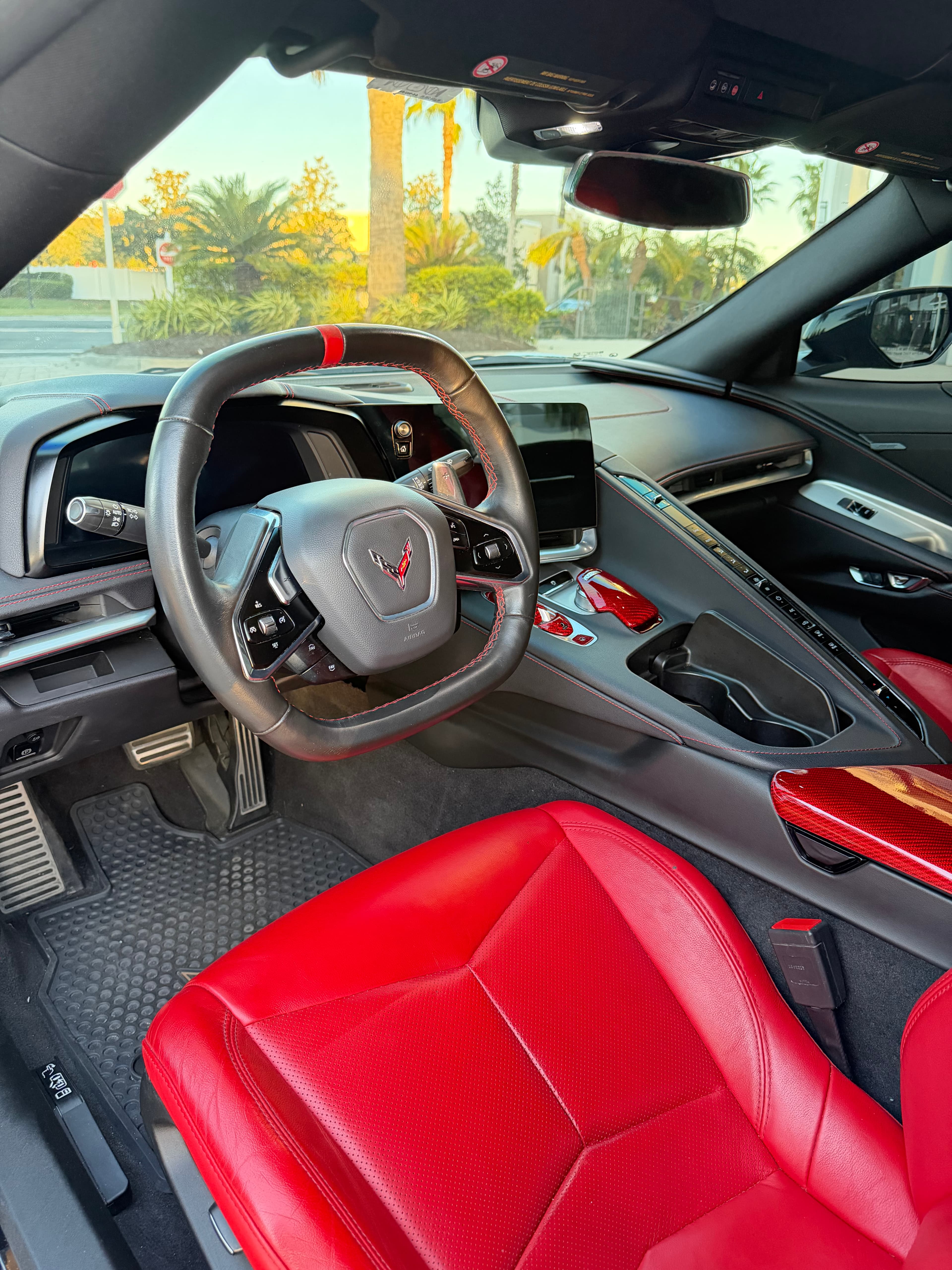 Corvette interior featuring red leather seats, black steering wheel, and red carbon fiber accents.